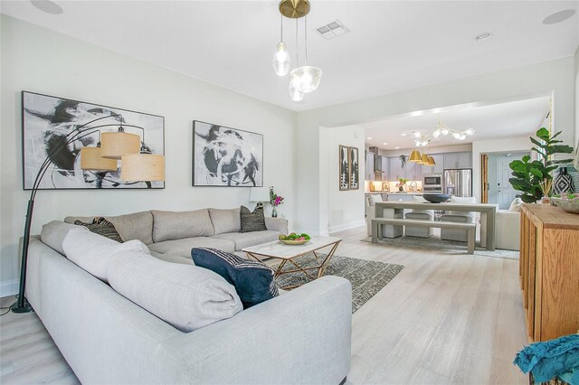 living area featuring light wood-style flooring, visible vents, and baseboards