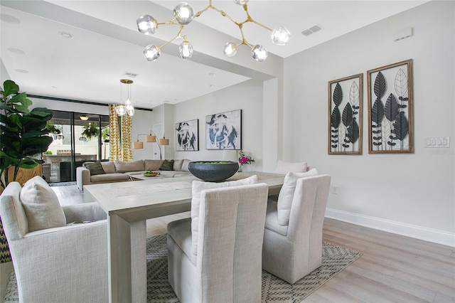 dining area with light wood-style floors, visible vents, a notable chandelier, and baseboards