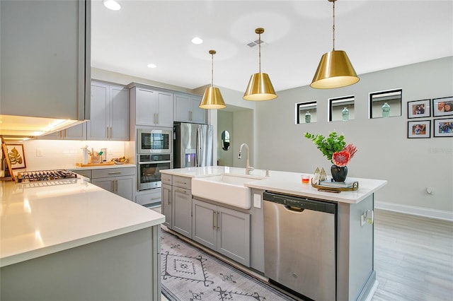 kitchen featuring appliances with stainless steel finishes, a sink, visible vents, and gray cabinetry