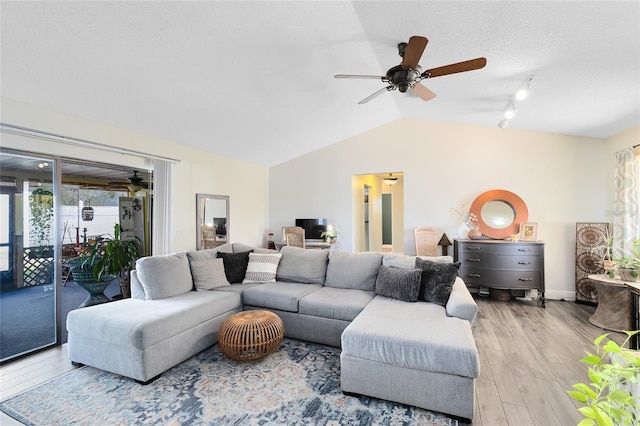 living area with vaulted ceiling, ceiling fan, light wood-type flooring, and baseboards