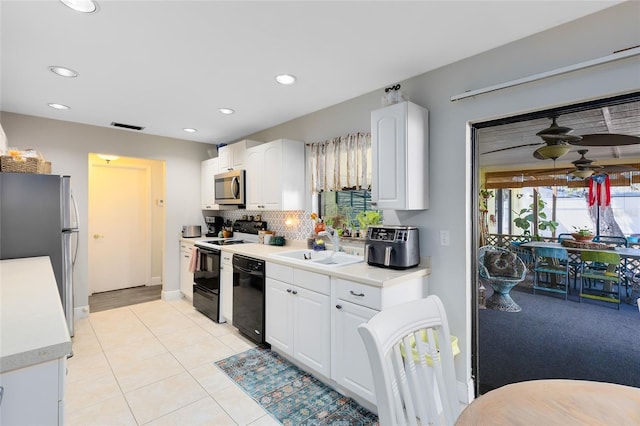 kitchen with appliances with stainless steel finishes, white cabinetry, a sink, and backsplash