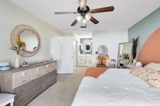 bedroom featuring ceiling fan, connected bathroom, visible vents, and light colored carpet