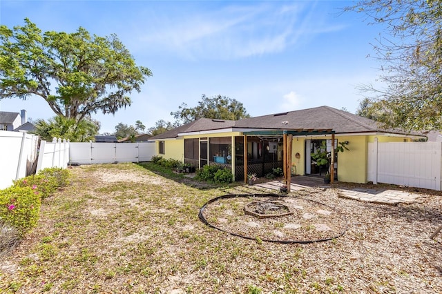 back of house featuring a fenced backyard, a sunroom, a lawn, a gate, and stucco siding