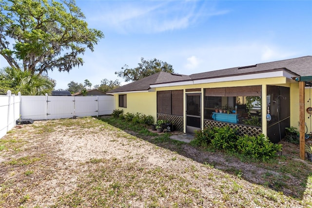 rear view of property featuring a sunroom, a gate, and a fenced backyard