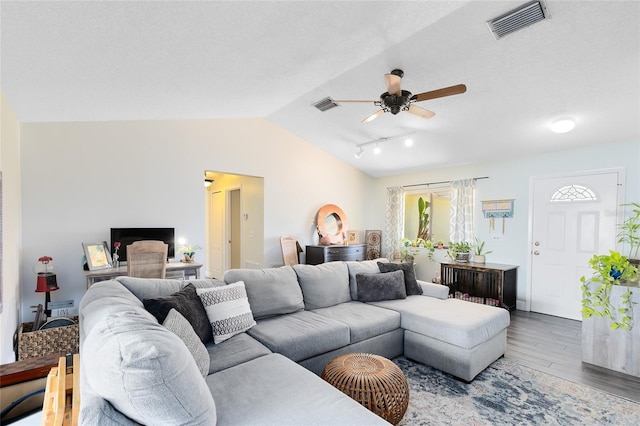 living room with lofted ceiling, wood finished floors, visible vents, and a ceiling fan