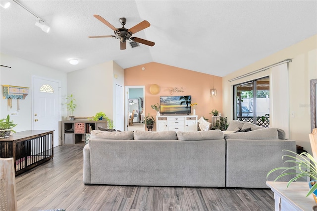 living area featuring ceiling fan, a textured ceiling, vaulted ceiling, and wood finished floors