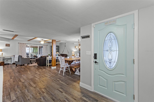 entrance foyer with dark wood finished floors, ceiling fan with notable chandelier, visible vents, and a textured ceiling