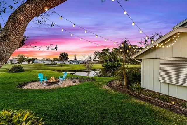 yard at dusk featuring a fire pit and a water view