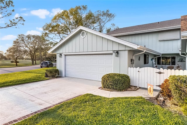 view of property exterior with board and batten siding, fence, a yard, a garage, and driveway