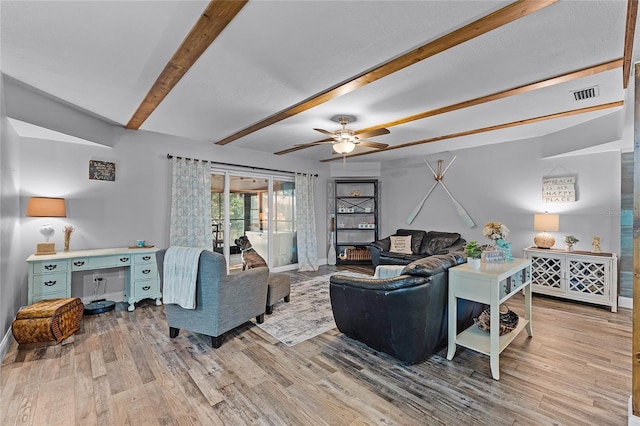 living area featuring light wood-type flooring, visible vents, beamed ceiling, baseboards, and ceiling fan