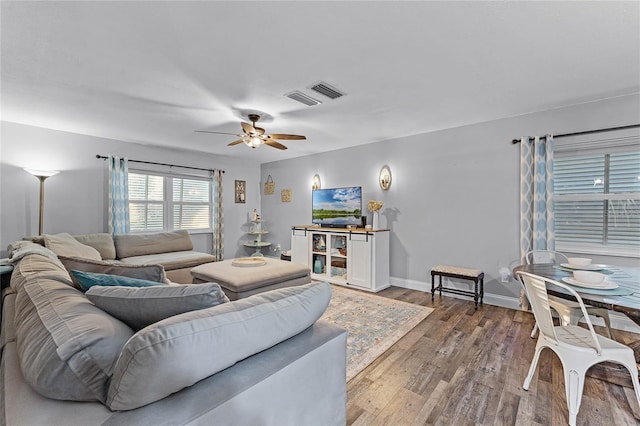 living area featuring visible vents, ceiling fan, baseboards, and wood finished floors