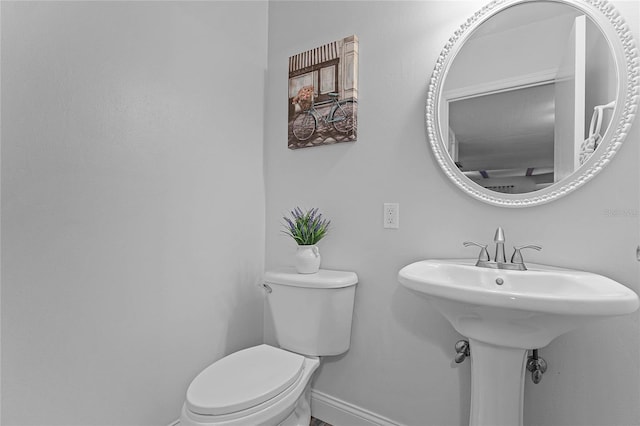 bathroom featuring toilet, baseboards, and a sink