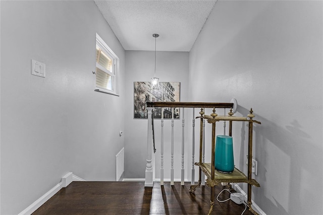 stairs featuring wood finished floors, baseboards, and a textured ceiling