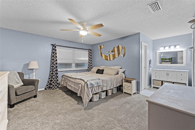 bedroom featuring visible vents, ensuite bathroom, a ceiling fan, baseboards, and light colored carpet