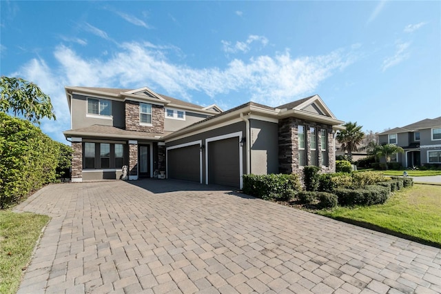 view of front facade with a garage, stone siding, decorative driveway, and stucco siding