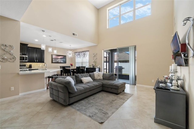 living area with a chandelier, visible vents, baseboards, and light tile patterned flooring