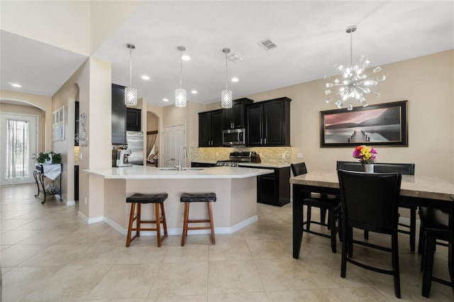 kitchen with arched walkways, dark cabinets, stainless steel appliances, a breakfast bar, and visible vents