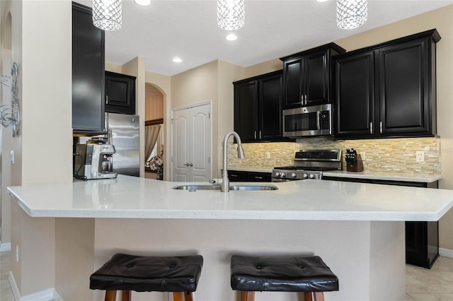 kitchen featuring arched walkways, a sink, stainless steel appliances, dark cabinetry, and backsplash