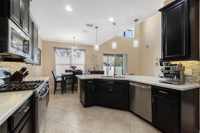 kitchen with stainless steel appliances, dark cabinetry, light countertops, a sink, and light tile patterned flooring