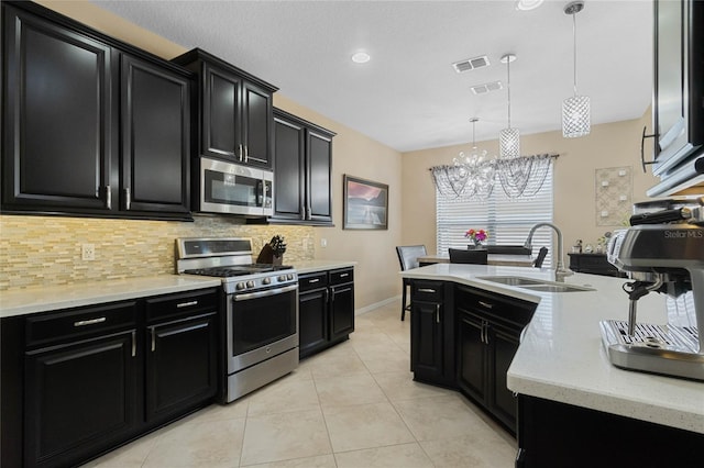 kitchen featuring dark cabinets, a sink, visible vents, appliances with stainless steel finishes, and backsplash