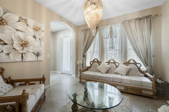 tiled living area featuring an inviting chandelier, baseboards, and arched walkways