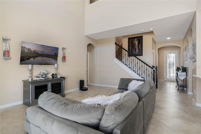 living room with arched walkways, stairway, baseboards, and tile patterned floors