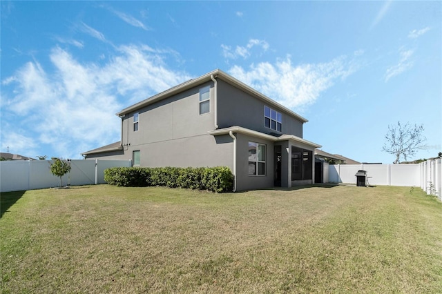 rear view of house featuring a fenced backyard, a lawn, and stucco siding