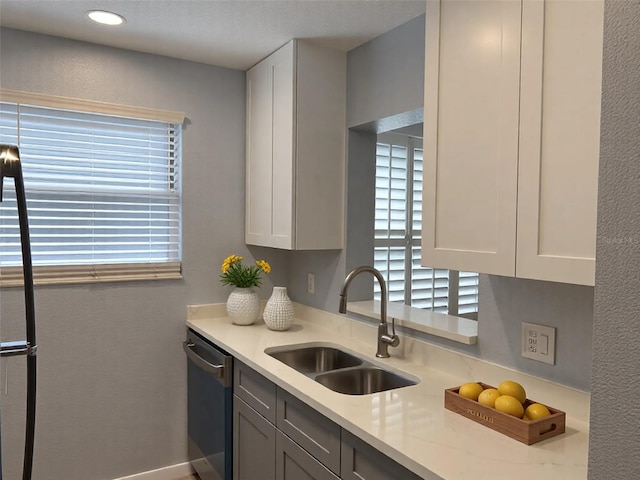 kitchen with stainless steel dishwasher, light countertops, a wealth of natural light, and a sink