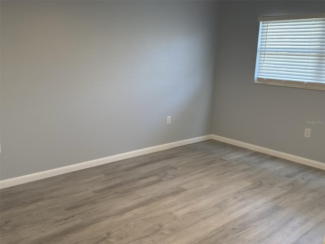 unfurnished room with baseboards and wood finished floors