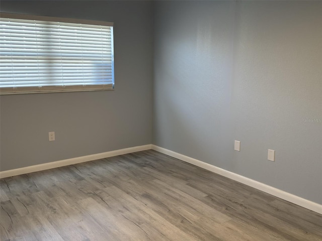 spare room featuring baseboards and wood finished floors