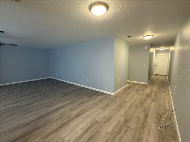 spare room featuring visible vents, baseboards, a textured ceiling, and wood finished floors