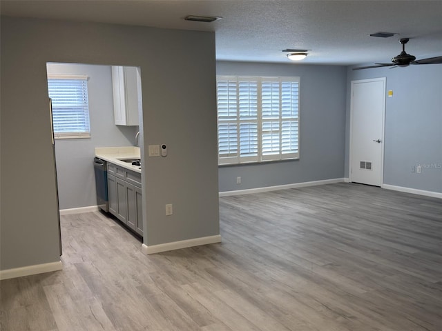 kitchen featuring visible vents, gray cabinets, a textured ceiling, light wood finished floors, and dishwasher