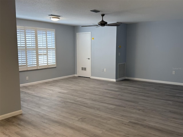 empty room featuring visible vents, ceiling fan, baseboards, wood finished floors, and a textured ceiling