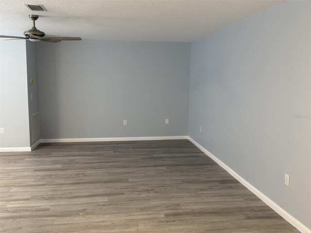 spare room with a textured ceiling, wood finished floors, visible vents, and ceiling fan