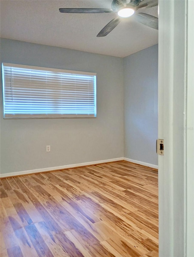 empty room featuring ceiling fan, baseboards, and wood finished floors