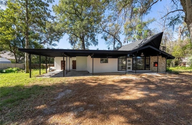 rear view of property featuring stone siding, a yard, a patio, and fence