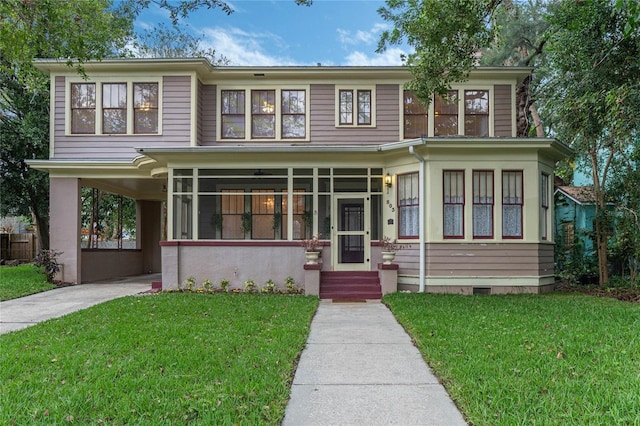 view of front facade with a carport, a sunroom, concrete driveway, and a front yard