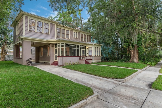 view of front of house featuring entry steps, driveway, a front lawn, and a sunroom