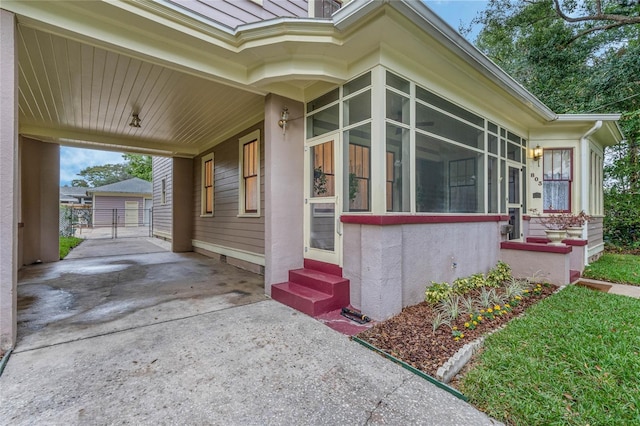 view of property exterior with entry steps, a sunroom, and concrete driveway