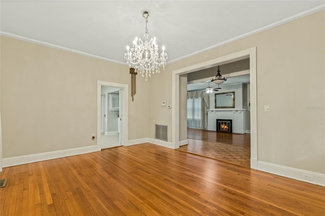 unfurnished dining area featuring ornamental molding, visible vents, a fireplace, and wood finished floors