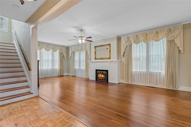 unfurnished living room with baseboards, ceiling fan, stairway, parquet flooring, and a fireplace