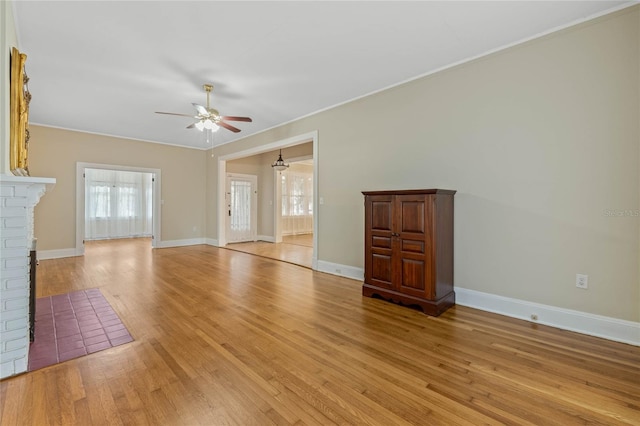 unfurnished living room with a brick fireplace, light wood-style flooring, baseboards, and a ceiling fan