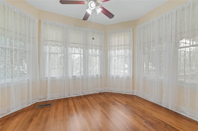 unfurnished room with hardwood / wood-style flooring, visible vents, and a ceiling fan