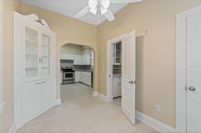 hallway with light tile patterned floors, baseboards, and arched walkways