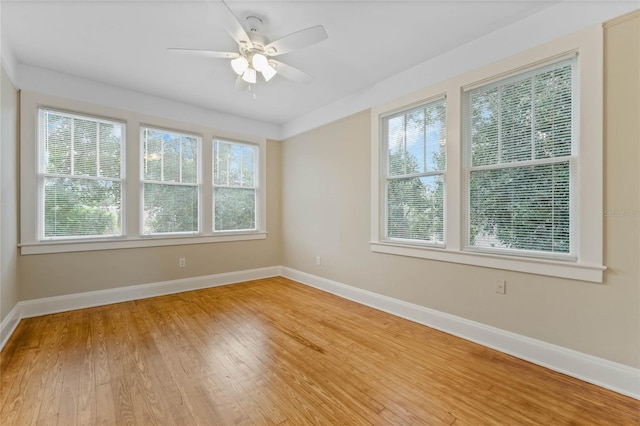 empty room with baseboards, ceiling fan, and light wood finished floors