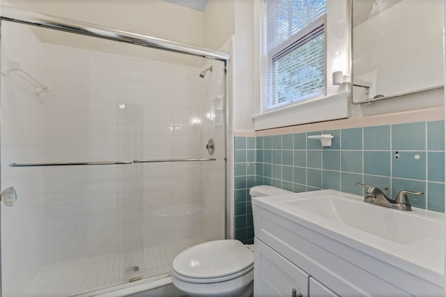 bathroom featuring a wainscoted wall, a stall shower, toilet, and tile walls