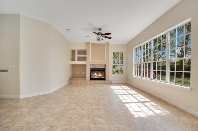 unfurnished living room with ceiling fan, visible vents, baseboards, tile patterned floors, and a glass covered fireplace