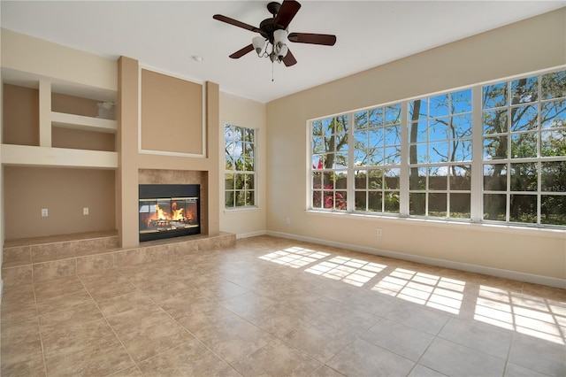 unfurnished living room featuring a glass covered fireplace, tile patterned flooring, and baseboards