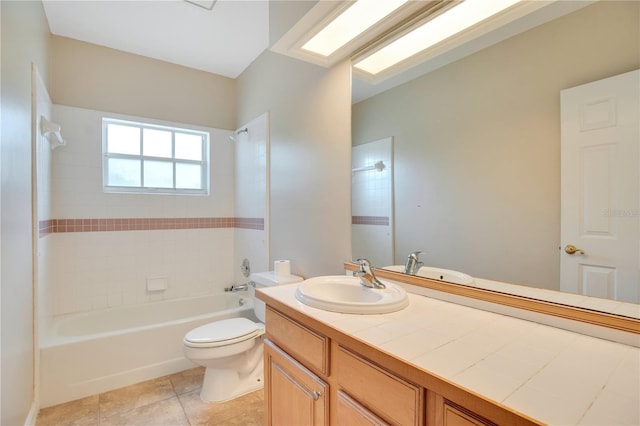 bathroom featuring a skylight, toilet, vanity, shower / tub combination, and tile patterned flooring