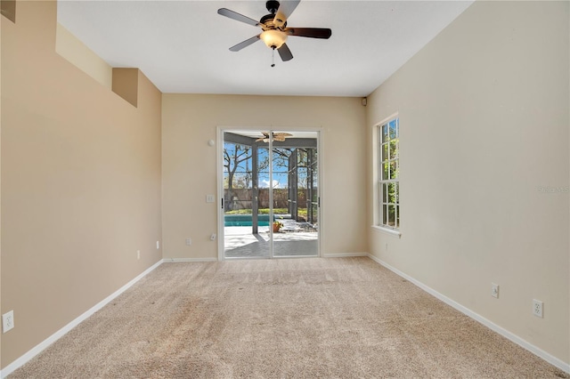 empty room featuring light carpet, a ceiling fan, a sunroom, and baseboards